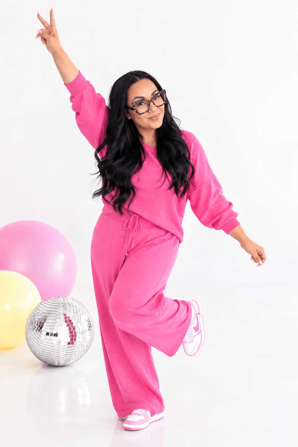 Marie Sales, founder of Creator Flow Collective, wearing pink and raising a peace sign